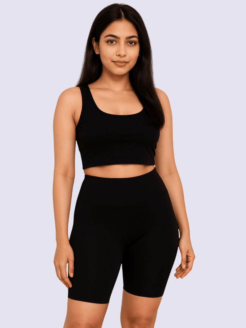 Woman wearing a black sports bra and shorts set on a light gray background