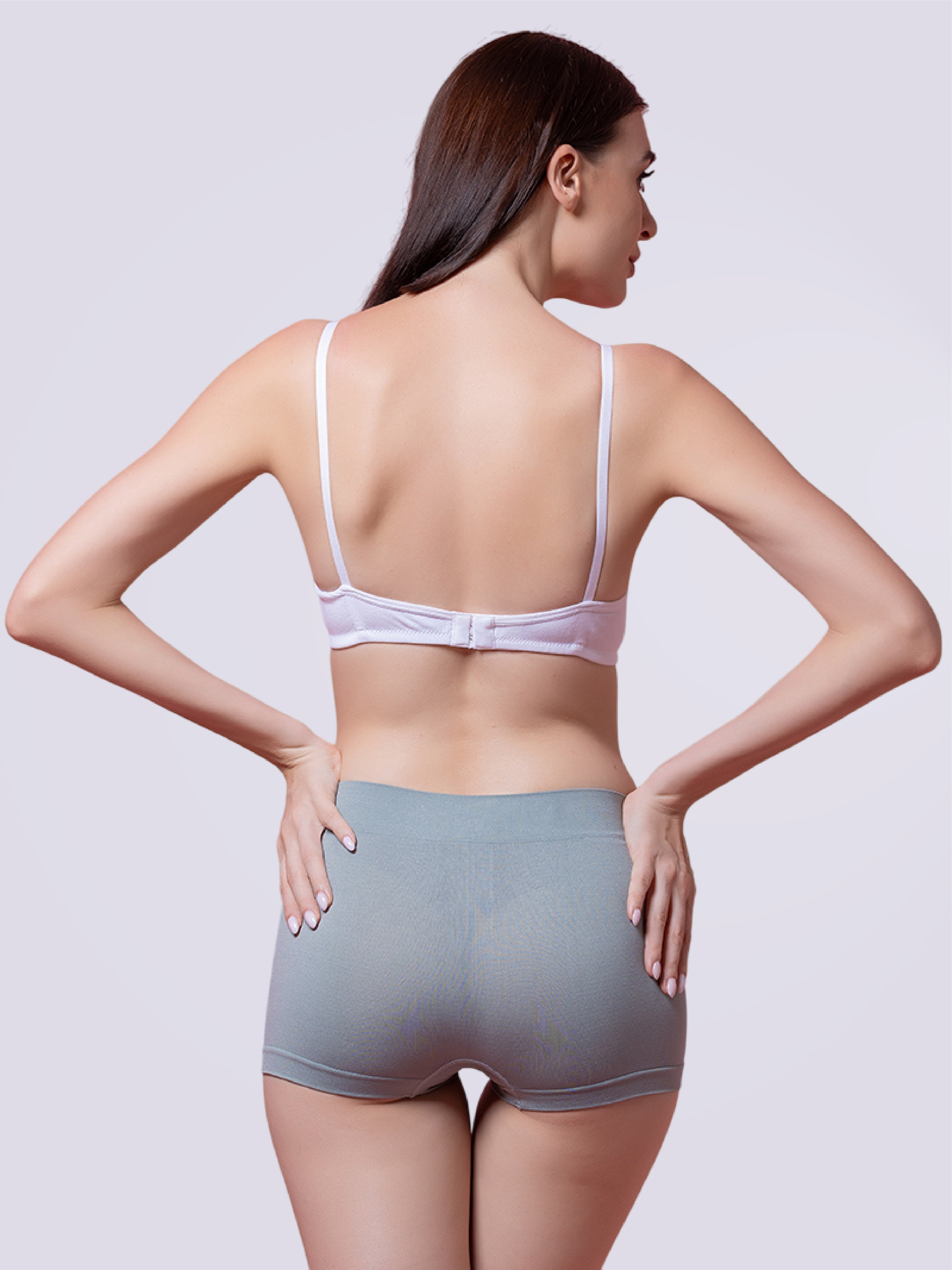 Woman wearing a white bra and gray shorts on a plain background