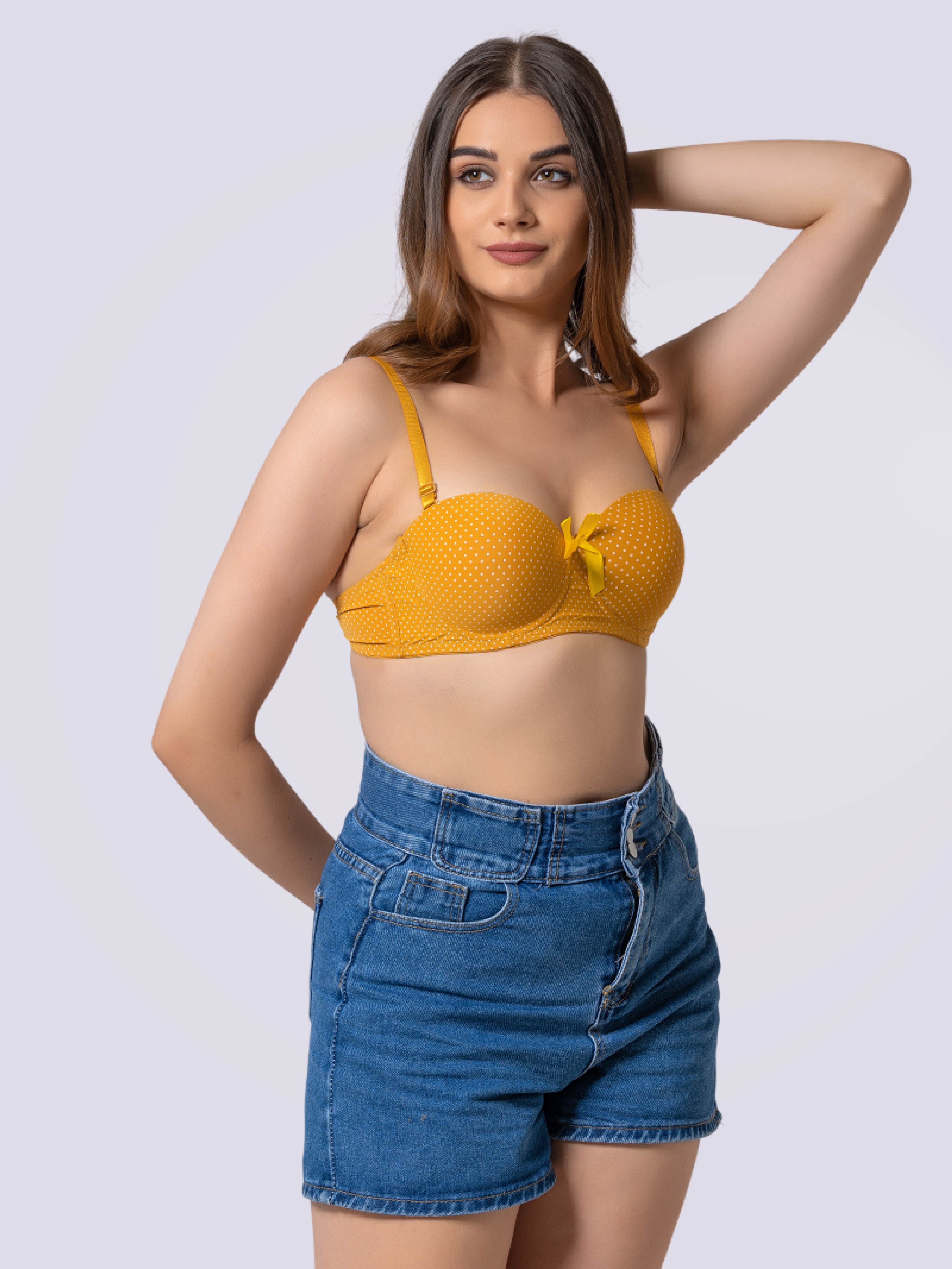 Woman wearing a yellow bralette and denim shorts on a white background