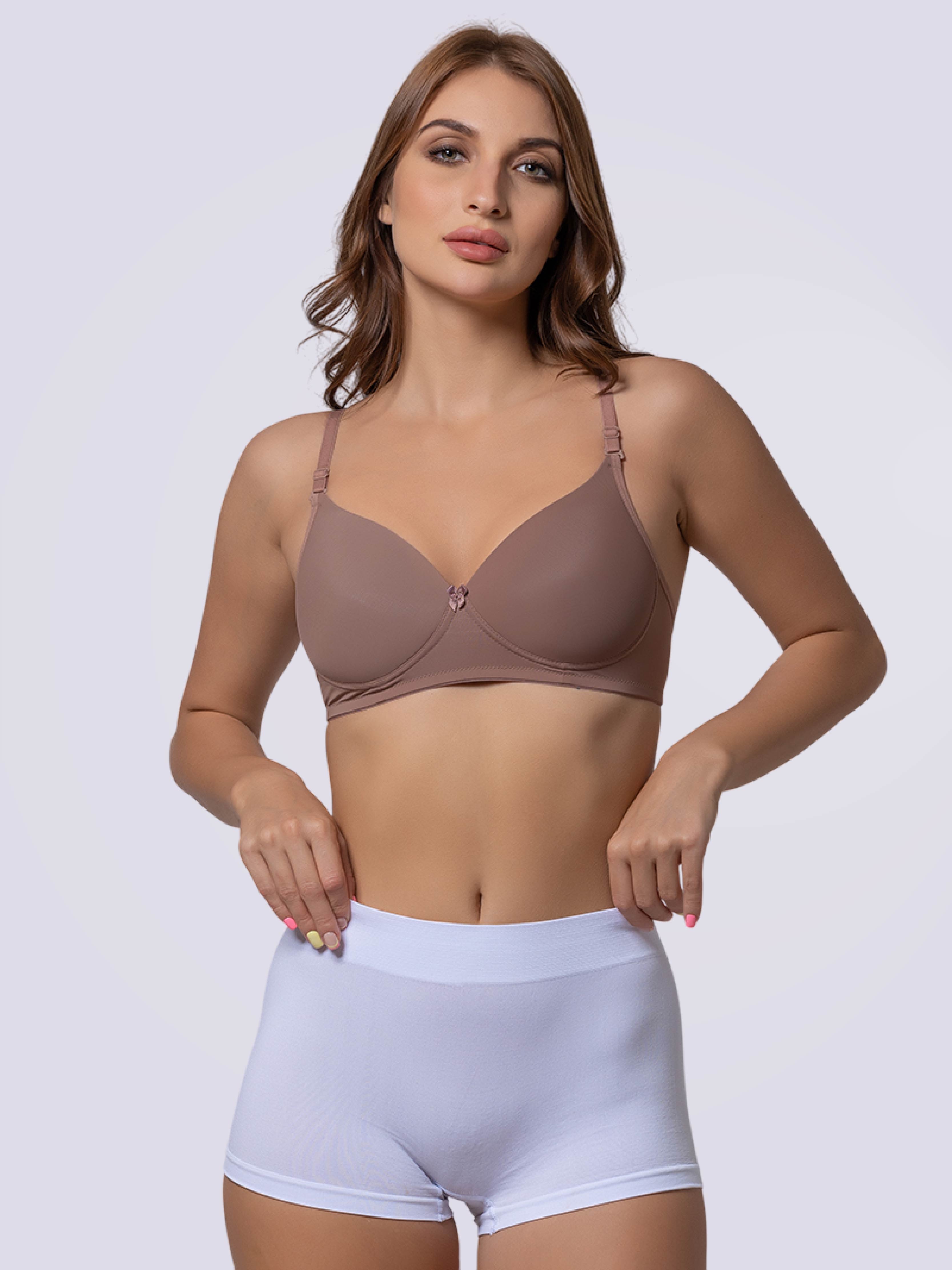 Woman wearing a brown bra and light purple shorts on a plain background