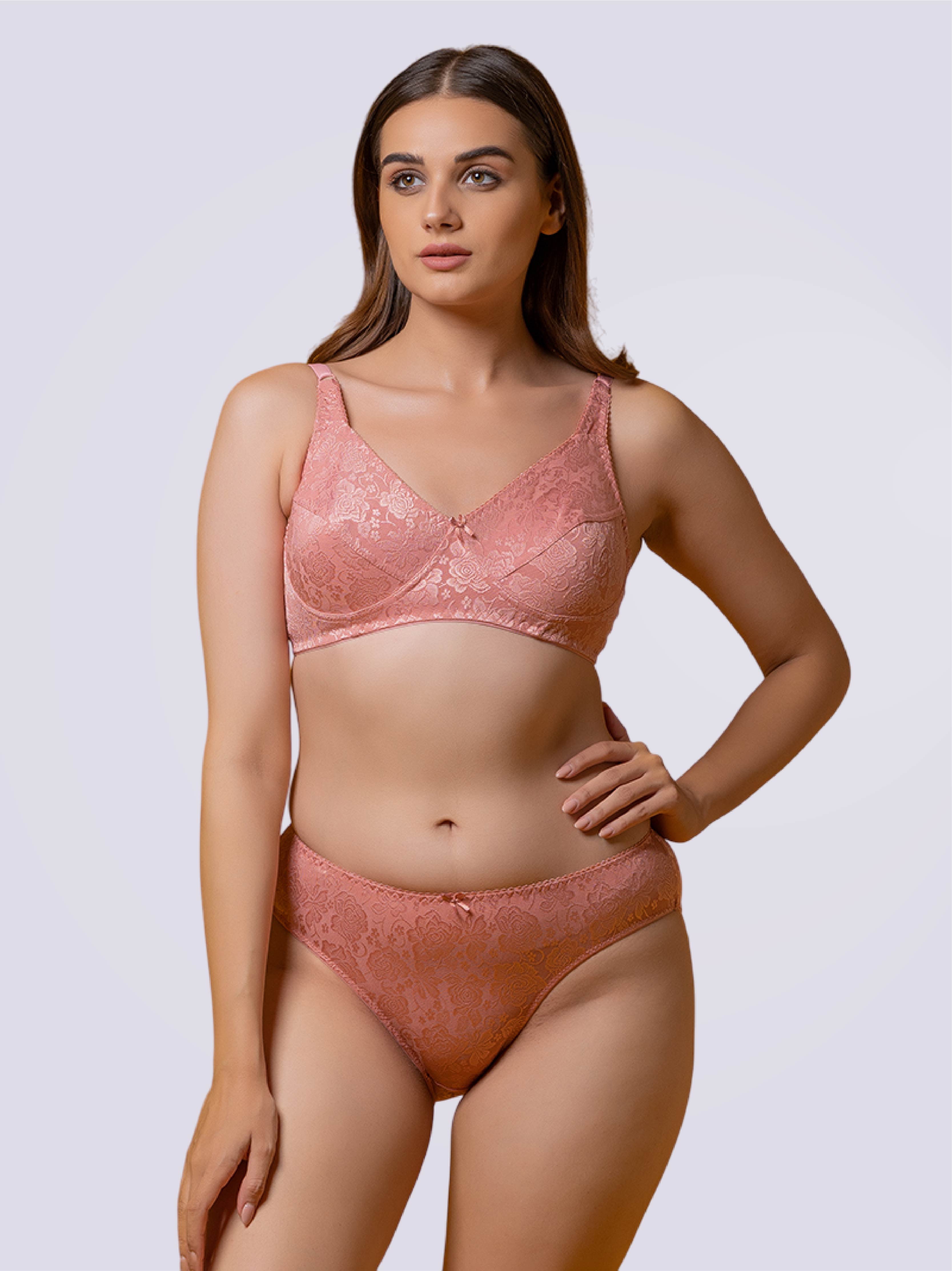 A woman wearing a pink lace bra and panties set.