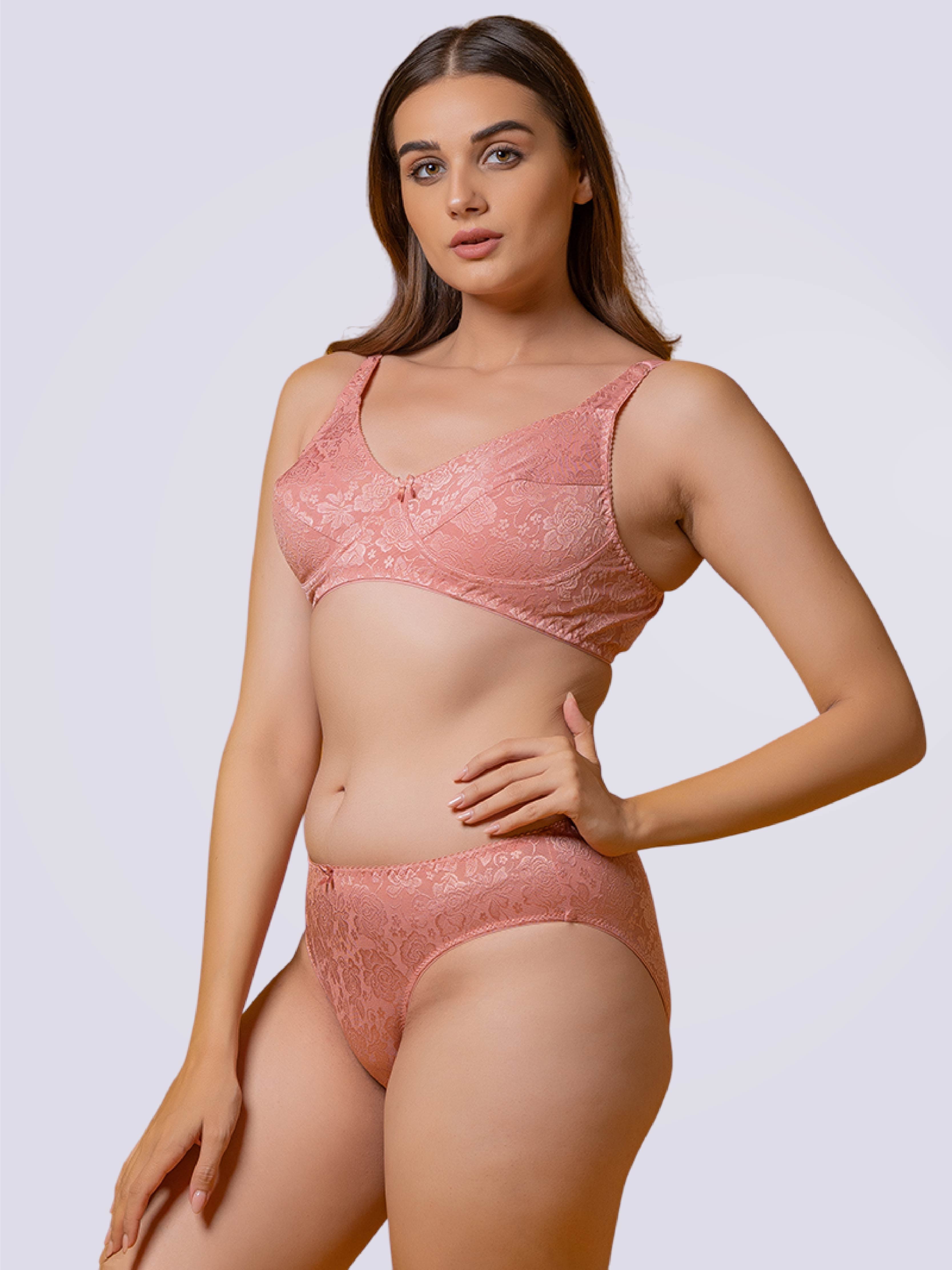 Woman wearing a pink lace lingerie set on a plain background