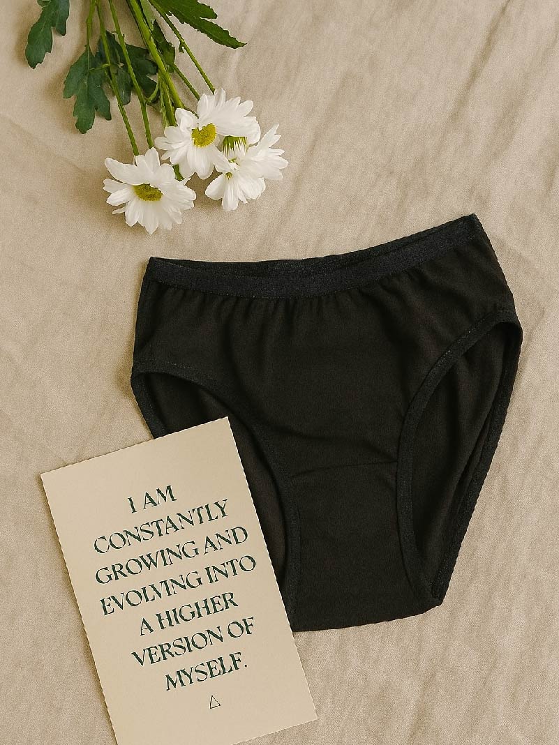 Black bloomers on a beige surface with white flowers and a motivational card.