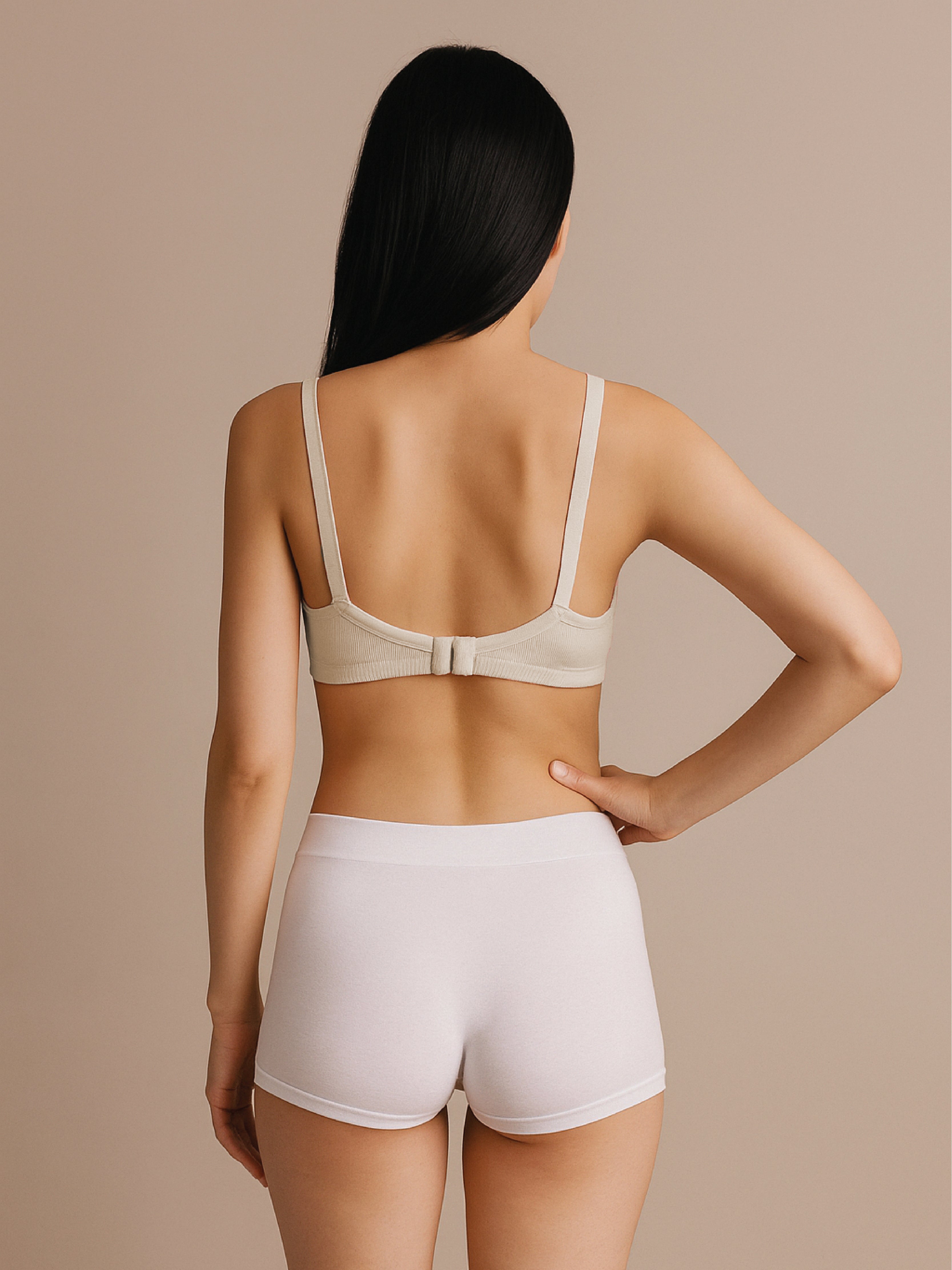 Woman wearing a beige bra and white shorts against a beige background