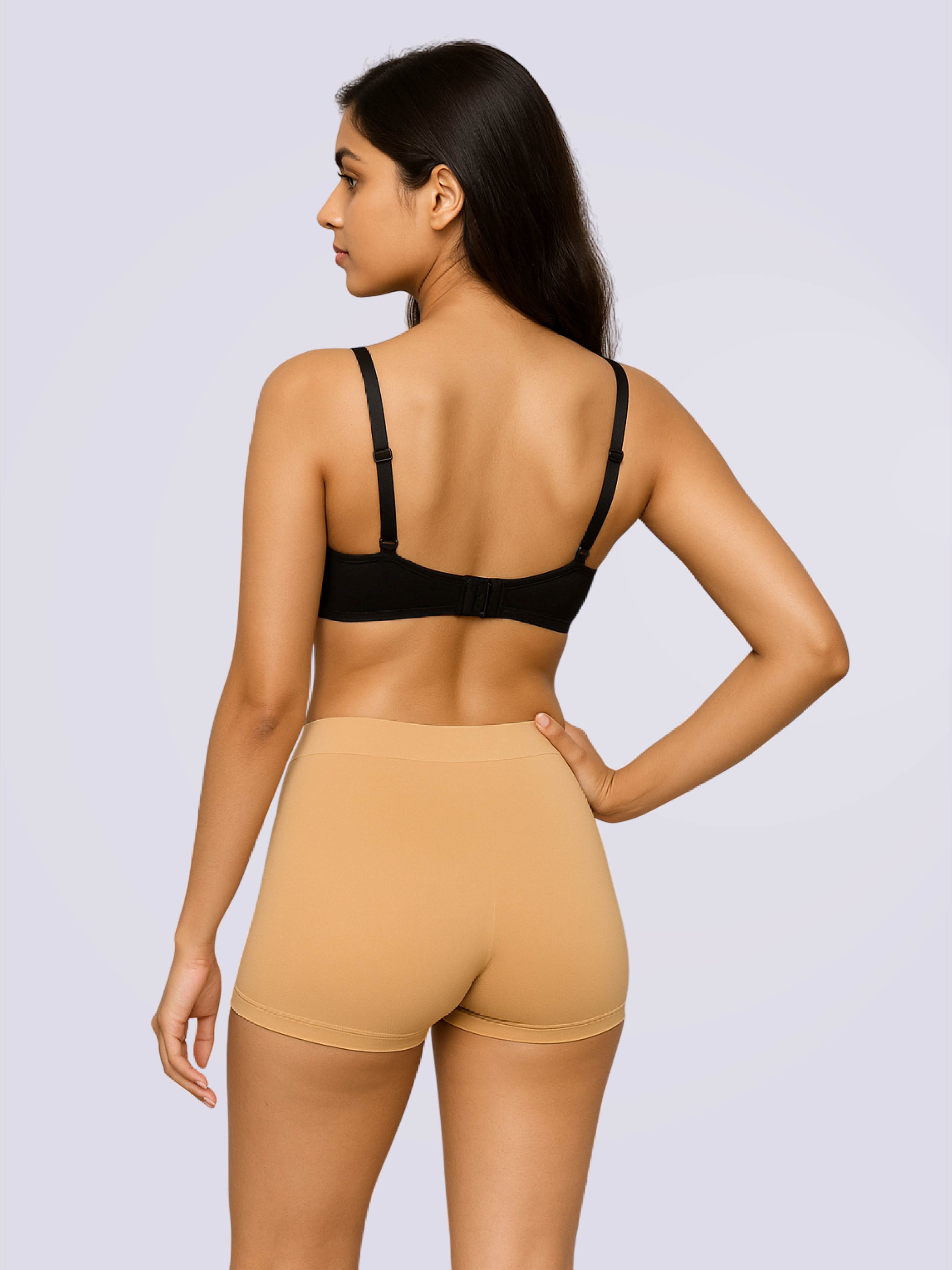 Woman wearing a black bra and beige shorts on a light gray background