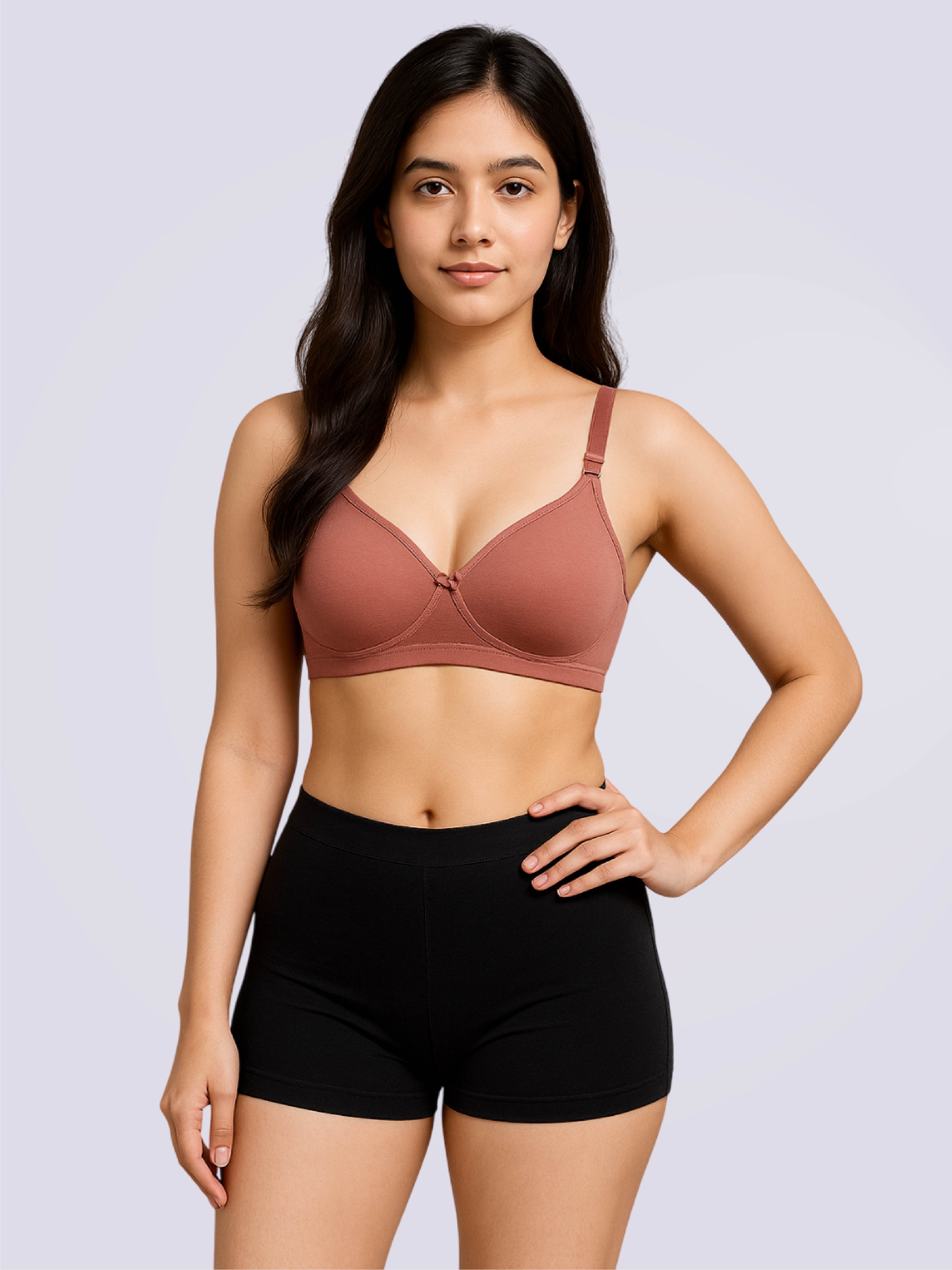 Woman wearing a brown bra and black shorts on a light gray background