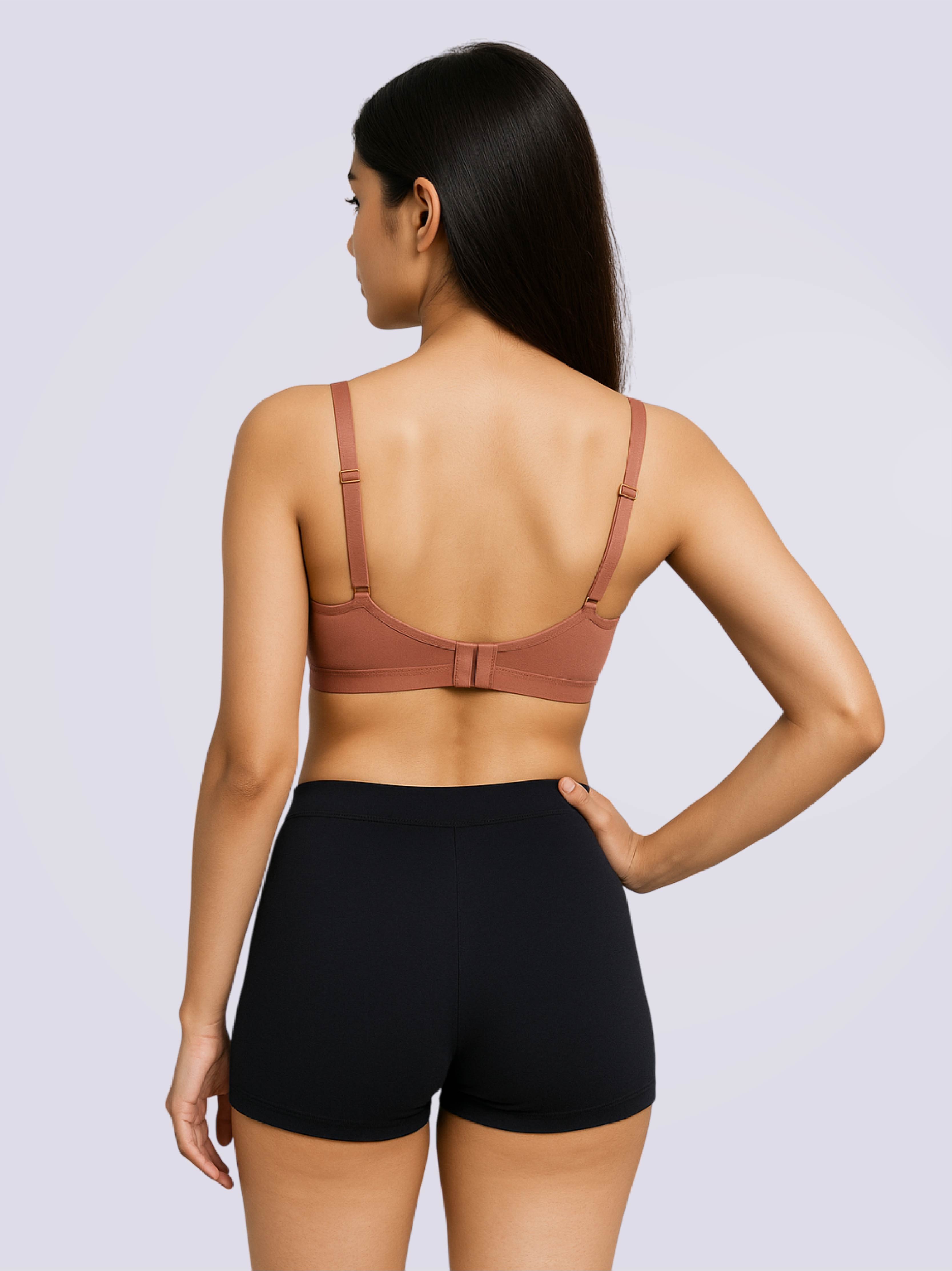 Woman wearing a brown bra and black shorts on a light gray background