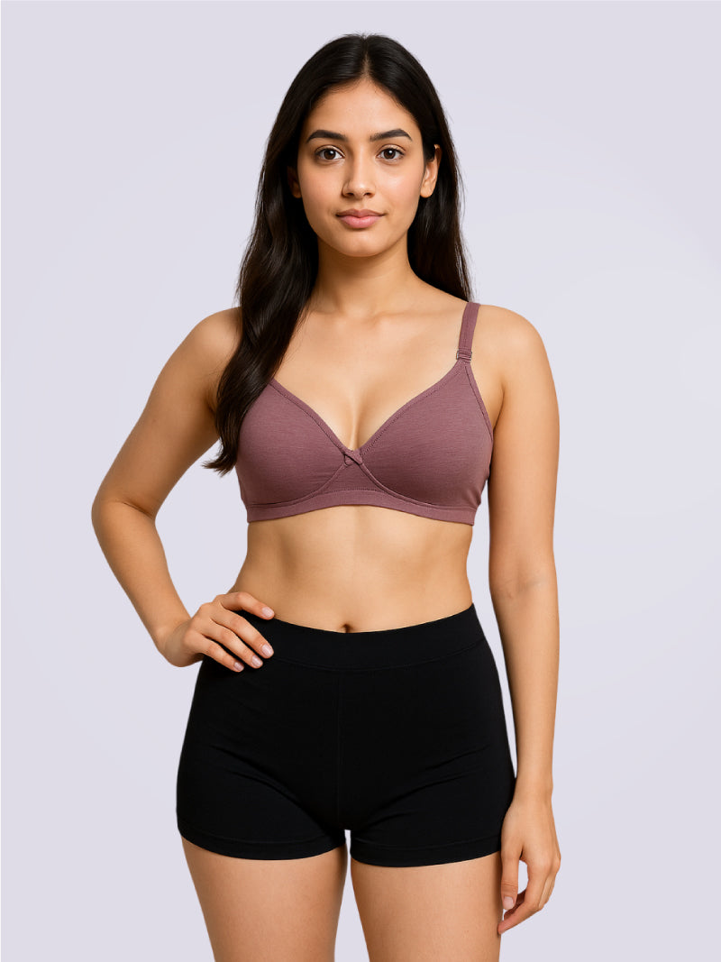 Woman wearing a mauve bra and black shorts on a light gray background