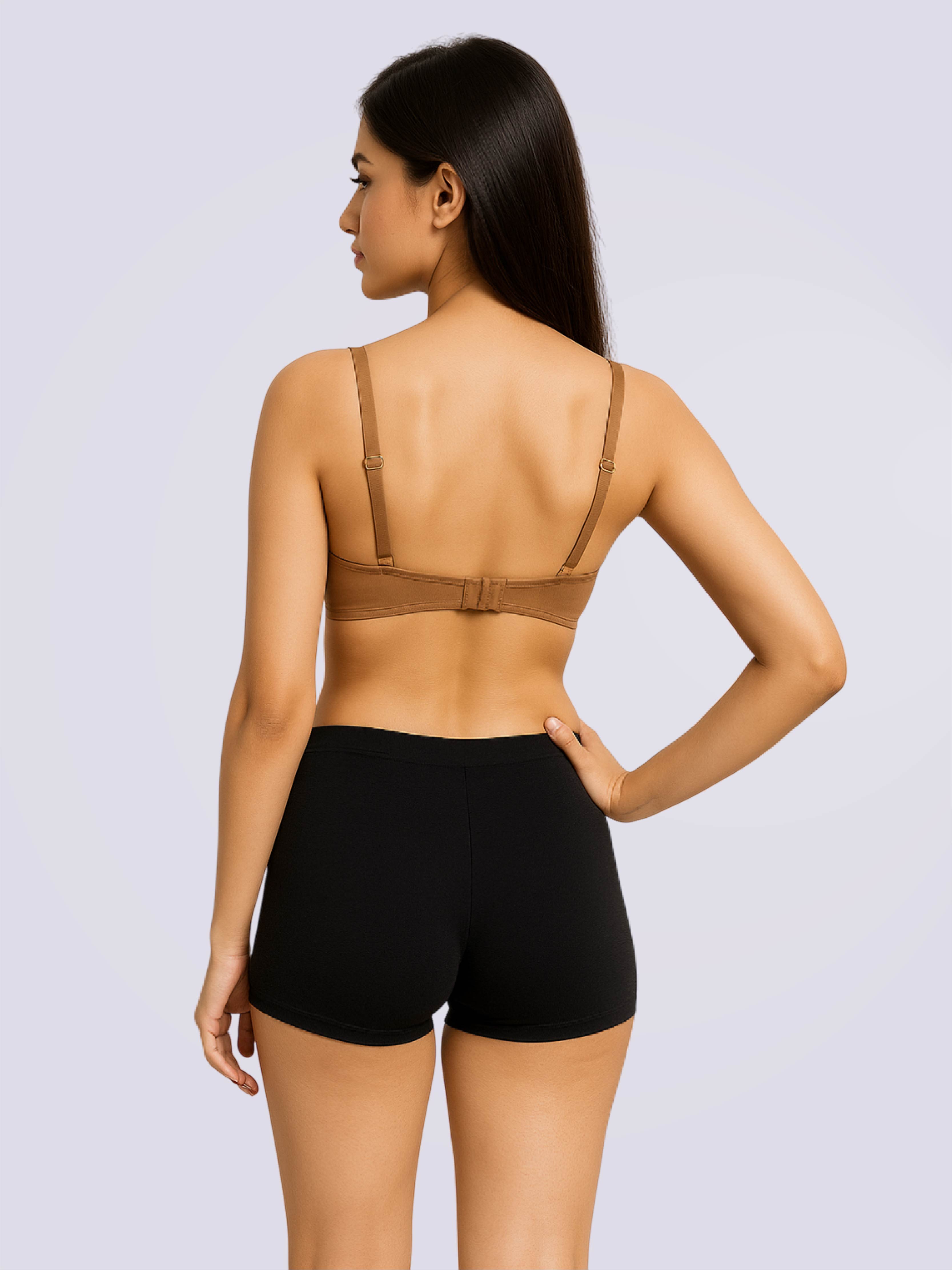 Woman wearing a brown bra and black shorts on a light gray background