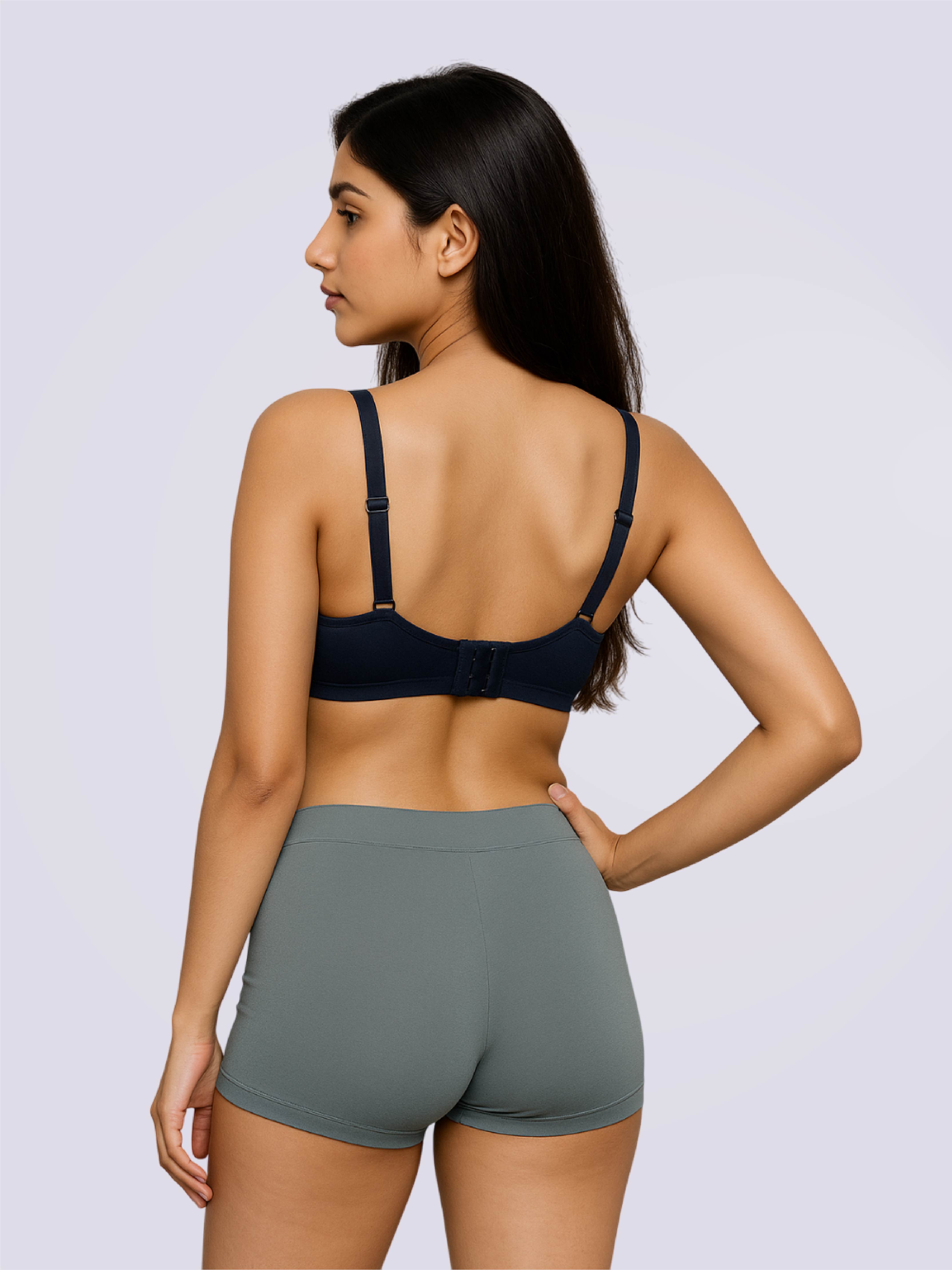 Woman wearing a dark blue bra and gray shorts on a light gray background