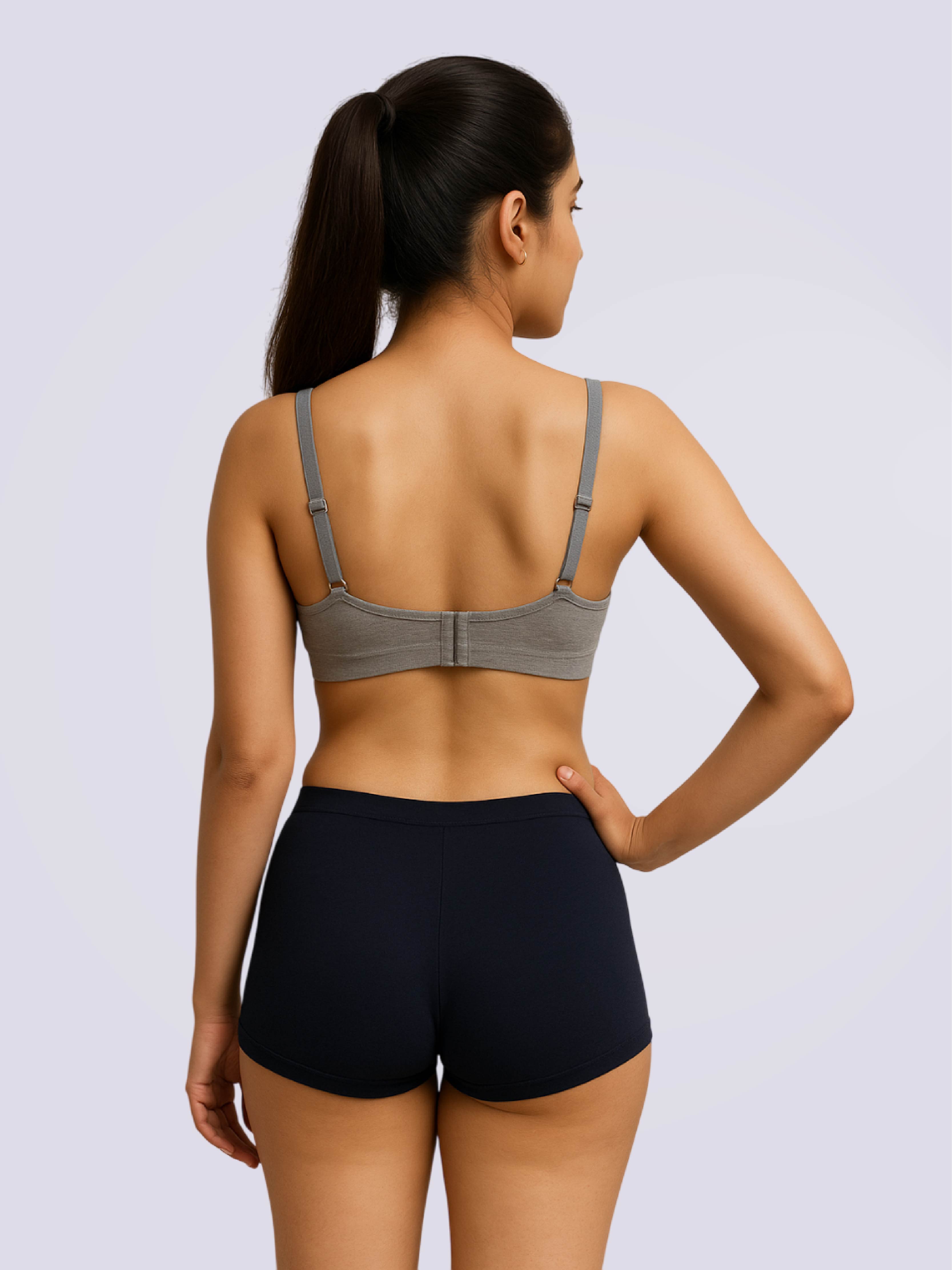 Woman wearing a gray bra and black shorts on a light gray background
