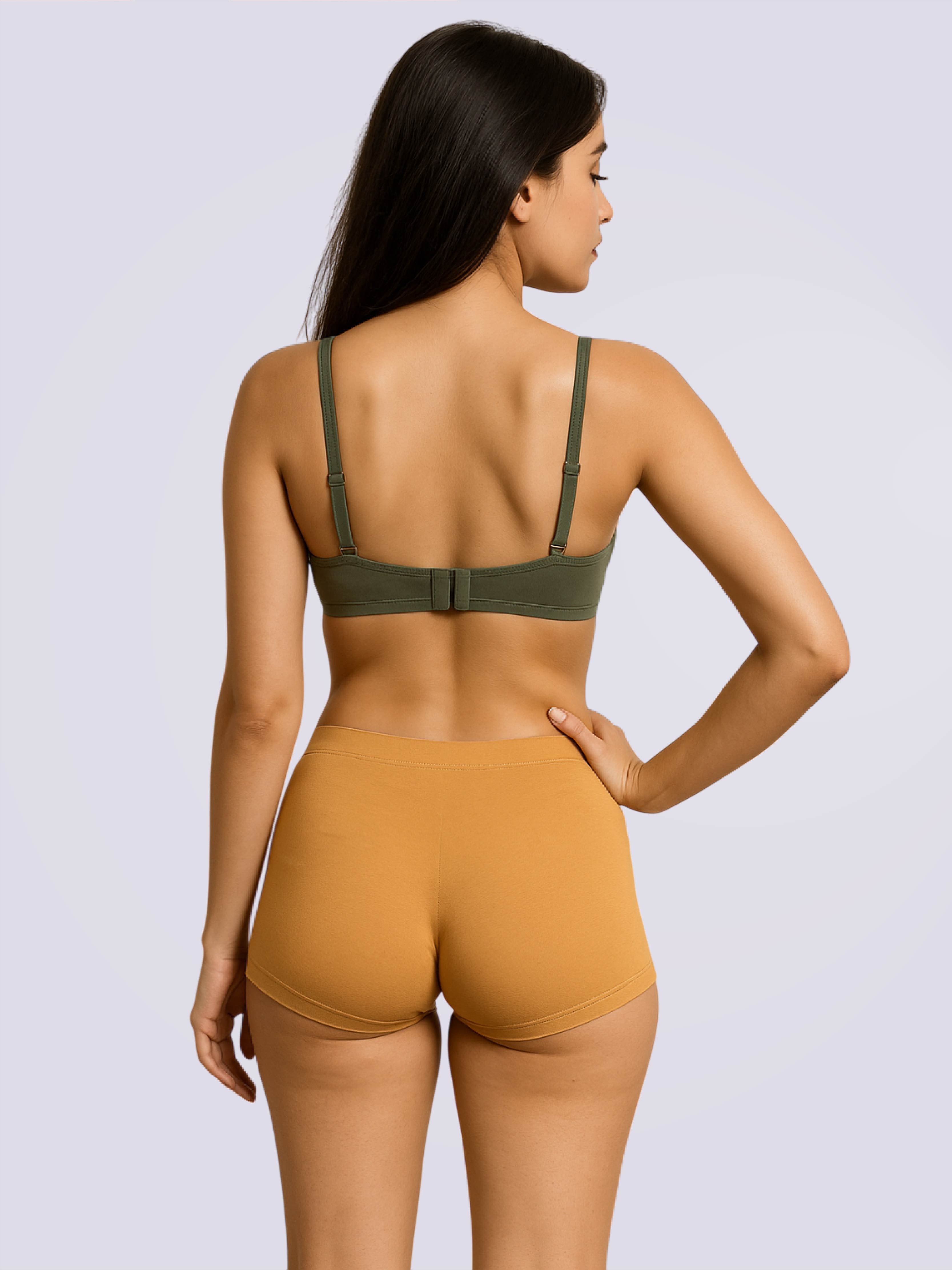 Woman wearing a green bra and mustard yellow shorts on a light gray background