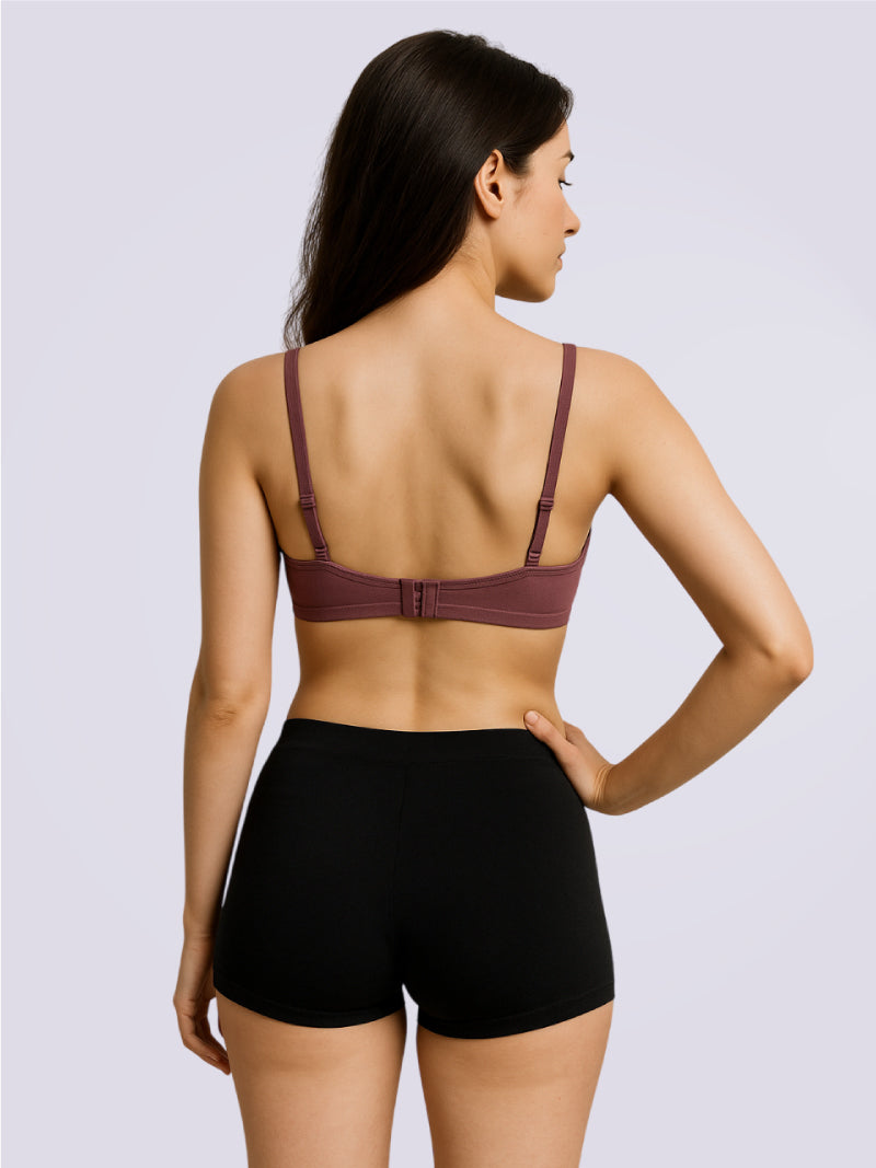 Woman wearing a purple bra and black shorts on a light gray background