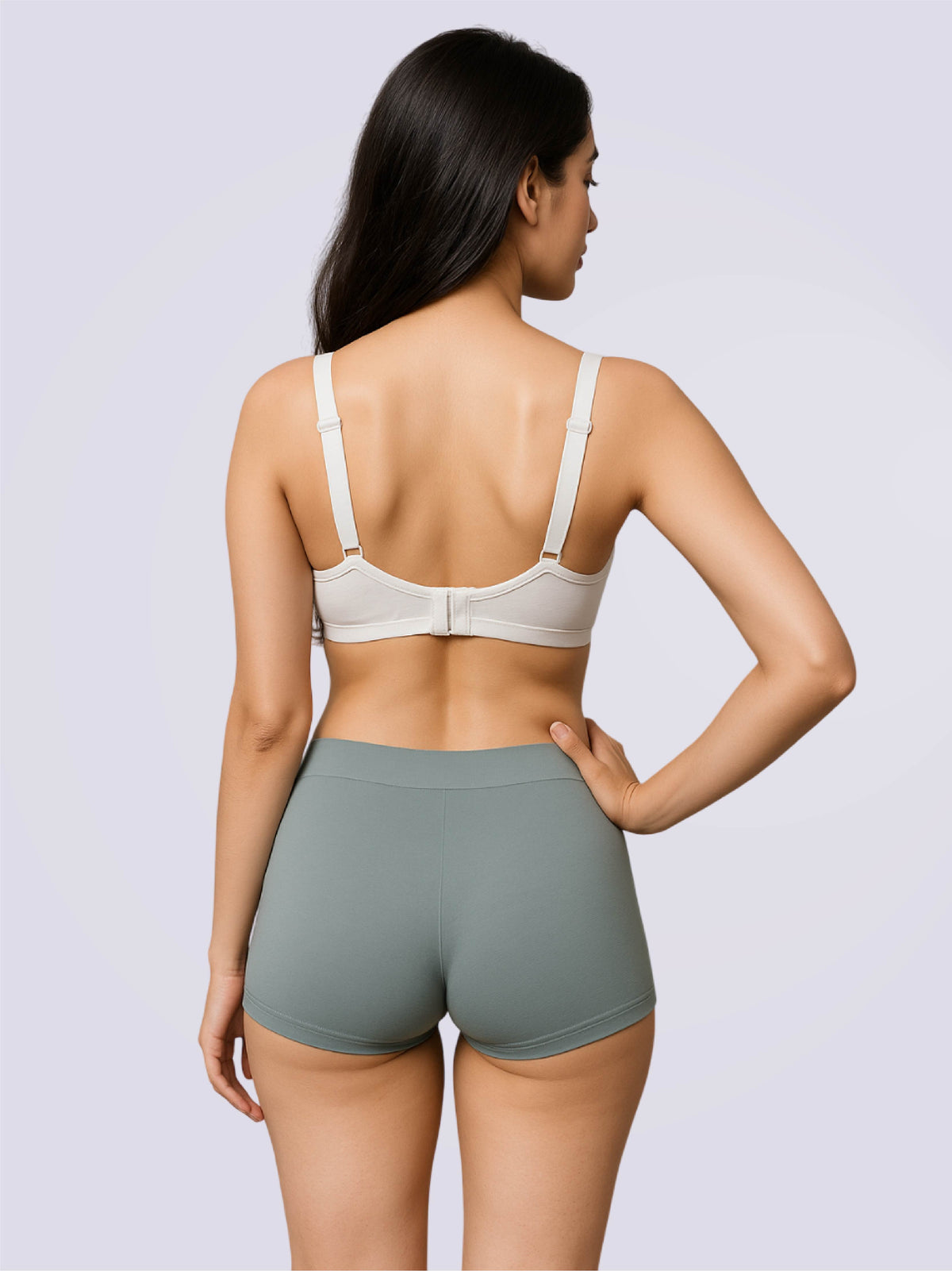 Woman wearing a white bra and gray shorts on a light gray background