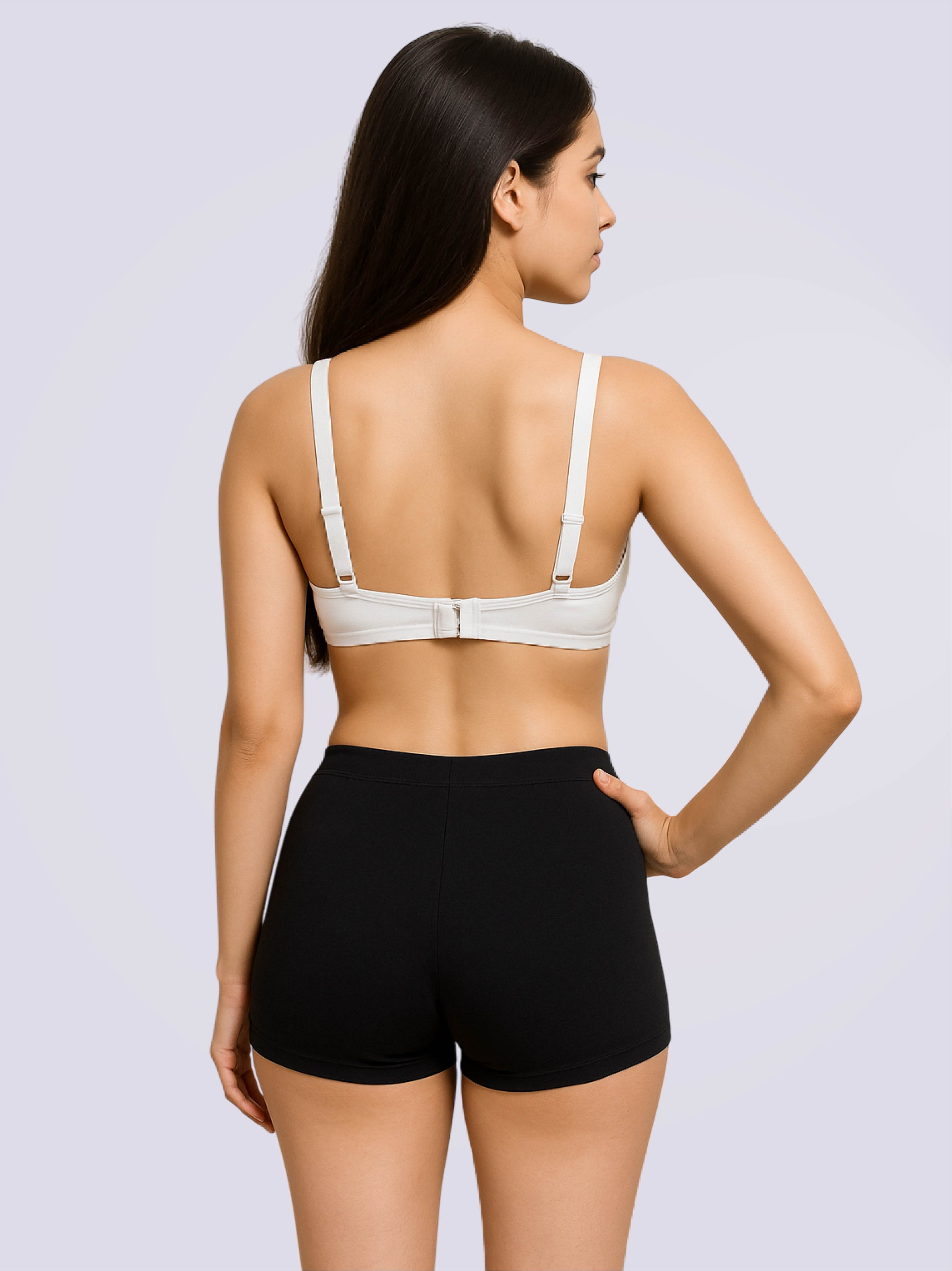 Woman wearing a white bra and black shorts on a light gray background